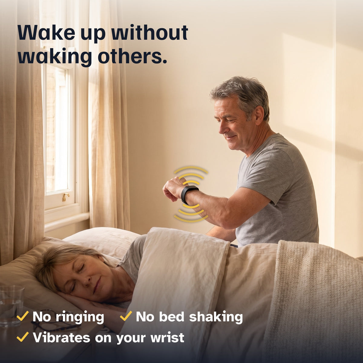Man in his late 50s sitting up in bed, looking at the black vibrating alarm band on his wrist while his wife sleeps. Wake up without waking others. No ringing, no bed shaking, vibrates on your wrist.